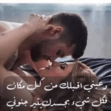 a man and a woman are kissing on a bed with arabic writing on it .