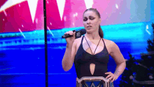 a woman in a black swimsuit is holding a microphone .