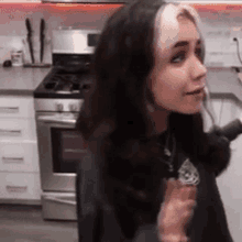 a woman is sitting in a kitchen in front of a stove and oven .