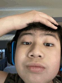 a young boy wearing headphones has his hand on his head