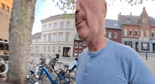 a man in a blue shirt stands in front of a row of parked bicycles