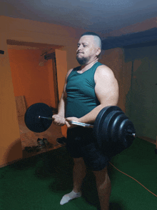 a man in a green tank top holds a barbell