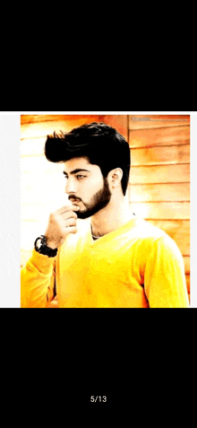 a man with a beard wearing a yellow sweater and a watch