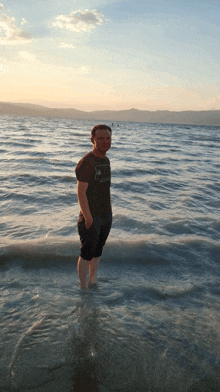 a man standing in the water wearing a t-shirt that says adidas