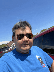 a man wearing sunglasses and a blue shirt with a picture of a man on it