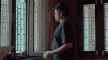 a man in a black shirt looks out of a window