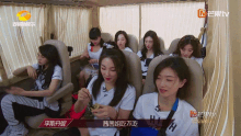 a group of women are sitting in a bus with a chinese tv logo on the bottom left