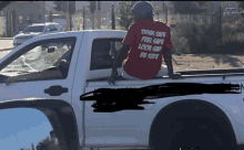 a man in a red shirt that says think safe feel safe look safe be safe sits on the back of a truck