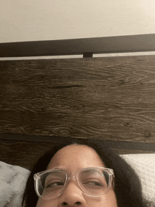 a woman wearing glasses is laying on a bed with her eyes closed