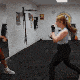 a woman is practicing martial arts in a gym with a sign on the wall that says ' karate and kick boxing '