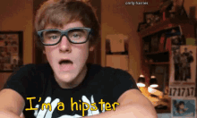 a young man wearing glasses and a t-shirt that says i 'm a hipster