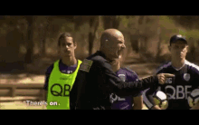 a man in a yellow vest that says " there 's on " stands in front of a group of soccer players