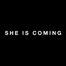 a black background with the words `` she is coming '' in white letters .