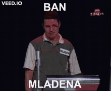 a man stands in front of a screen that says ban mladena on it