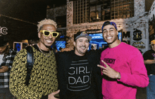 a man wearing a girl dad t-shirt poses with two other men