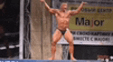 a man in a bathing suit is standing on a stage with his arms in the air .