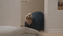 a woman is kneeling down in front of a bed in a room .