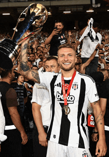 a man in a beko jersey holds up a trophy in front of a crowd