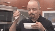 a man is eating soup from a bowl with a spoon in his mouth .