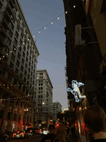 a neon sign with a monkey on it hangs from the side of a building in a city