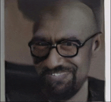 a bald man with glasses and a beard is smiling