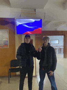 two young men are standing in front of a russian flag