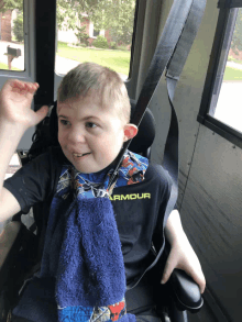 a young boy wearing an under armour shirt is sitting in a wheelchair