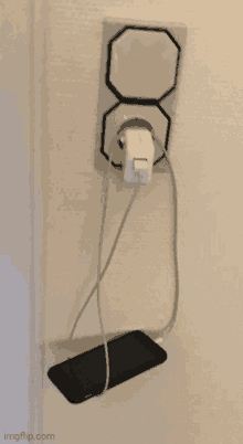 a cell phone is plugged into a charger in a wall outlet