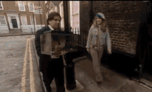 a man and a woman are walking down a sidewalk in front of a building with a sign that says boston three