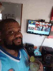 a man is holding a drink in front of a television that says xim baobab got