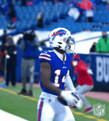 a football player in a buffalo bills uniform is holding a football .