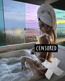 a woman in a bathtub with a towel wrapped around her head has a censored sign taped to her chest