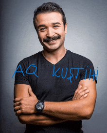 a man with a mustache is wearing a black shirt and a watch with aq written on it