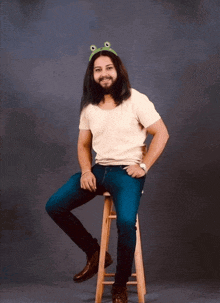 a man wearing a frog headband is sitting on a wooden stool