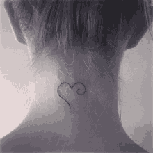 a woman has a small tattoo of a heart on the back of her neck