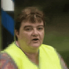 a woman is wearing a yellow vest and making a funny face .