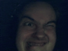 a close up of a man 's face making a funny face in the dark .