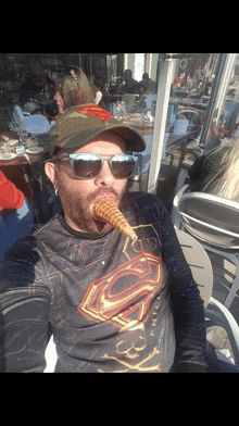 a man wearing a superman shirt is eating a waffle cone