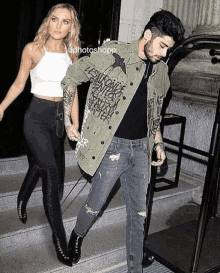 a man and a woman are holding hands and walking down stairs .