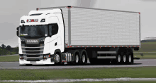 a white scania truck is driving on a road