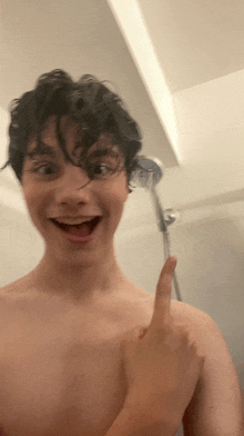 a shirtless young man is taking a shower and smiling