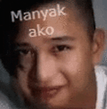 a close up of a man 's face with the words `` manyak ako '' written on his forehead .