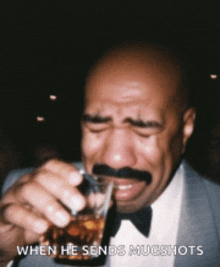 a man with a mustache is drinking from a shot glass and crying