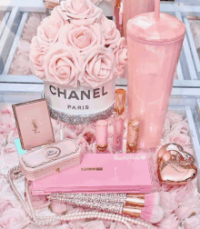 a chanel box filled with pink roses sits on a table surrounded by pink flowers