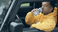 a man in a yellow hoodie is drinking from a can that says ice