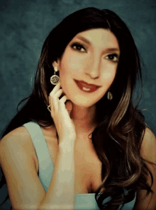 a woman wearing earrings and a ring is smiling for the camera