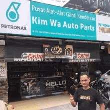 a man giving a thumbs up in front of a petronas sign