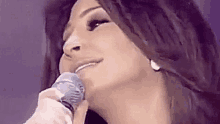 a woman is singing into a microphone on stage .