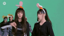 two girls wearing bunny ears are giving the thumbs down