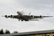 a large emirates airplane is flying over a roof